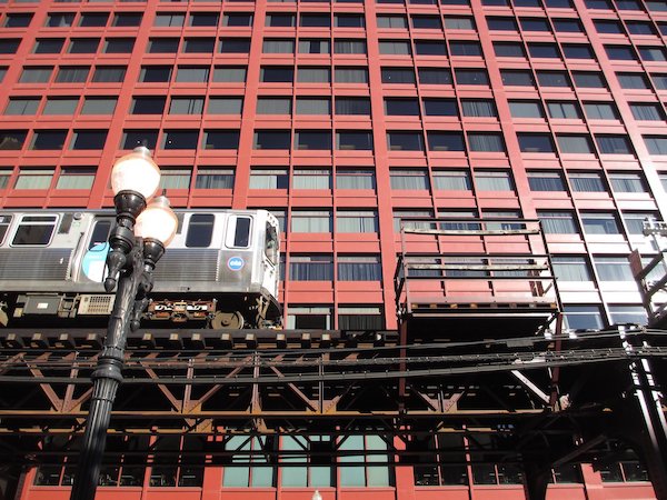 Chicago train on elevated track in front of red building