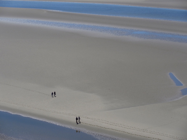 Two tiny figures walking along huge beach