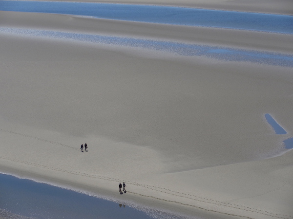 Two tiny figures walking along huge beach