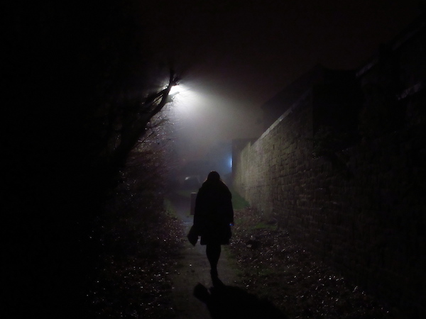 Shadowy figure in alleyway under streetlight