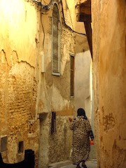 Woman in headscarf walking between high walls